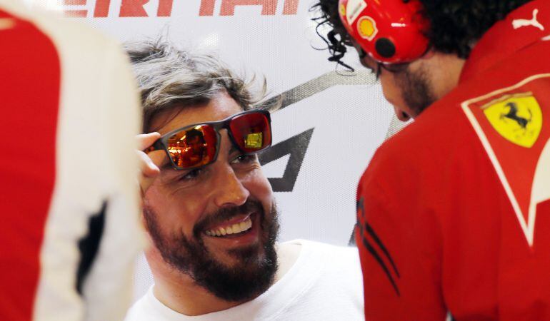 Fernando Alonso sonríe mientras habla con un miembro de su equipo