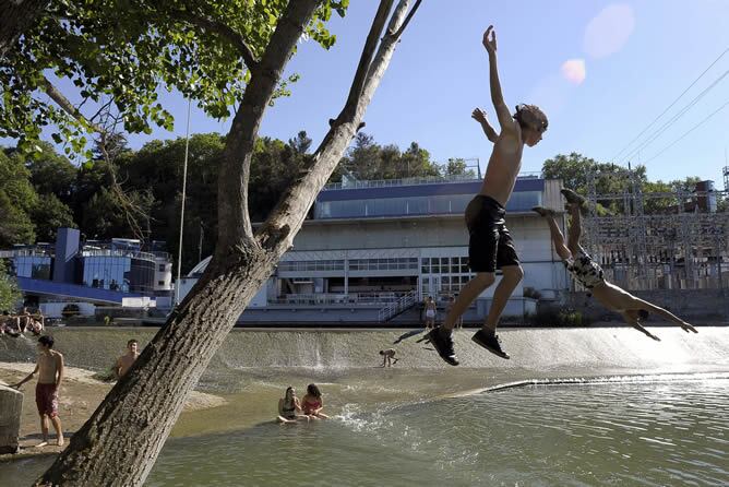 Varios jóvenes se refrescan en el río Arga en Pamplona para intentar mitigar las altas temperaturas registradas en la región.