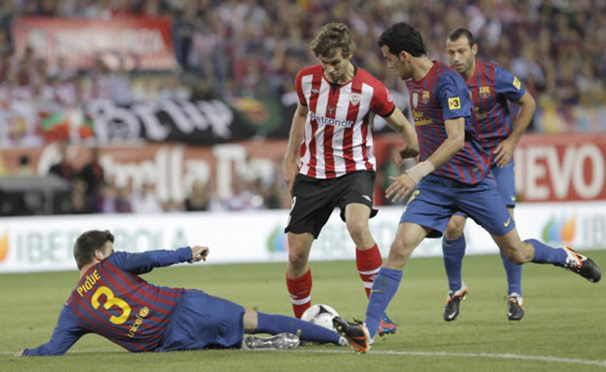 El delantero del Athletic de Bilbao Fernando Llorente (c) pelea un balón con los jugadores del FC Barcelona Gerard Piqué (i) y Sergio Busquets, en la final de la Copa del Rey de fútbol que se disputa esta noche en el estadio Vicente Calderón de Madrid. | 