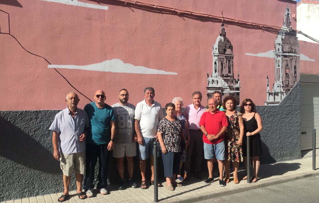 El concejal, Francisco Lechuga (quinto por la izqda) junto a vecinos del barrio posan ante el mural pintado en una fachada particular cedida para tal uso.