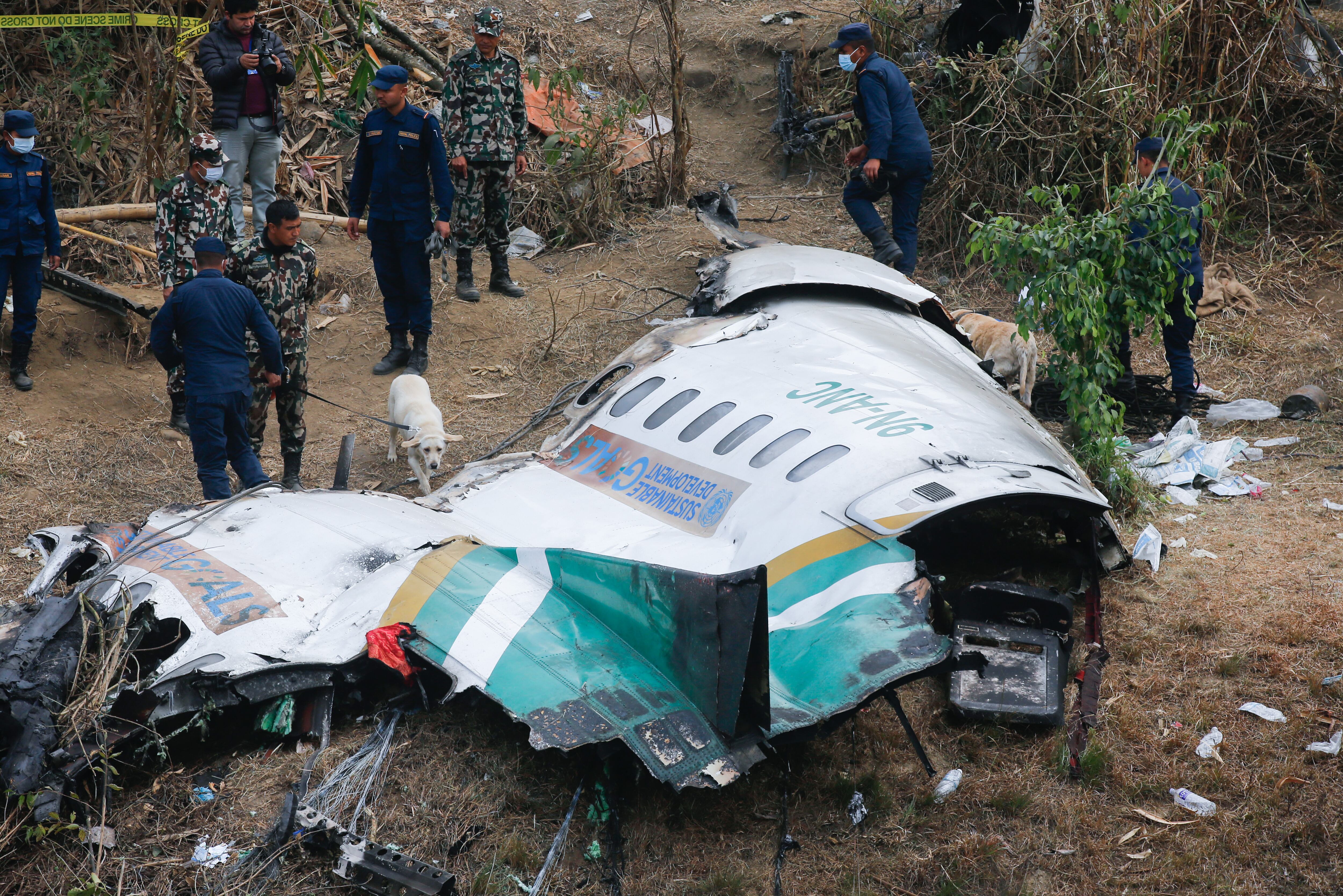 Las autoridades junto a un trozo del avión que se estrelló en Nepal.