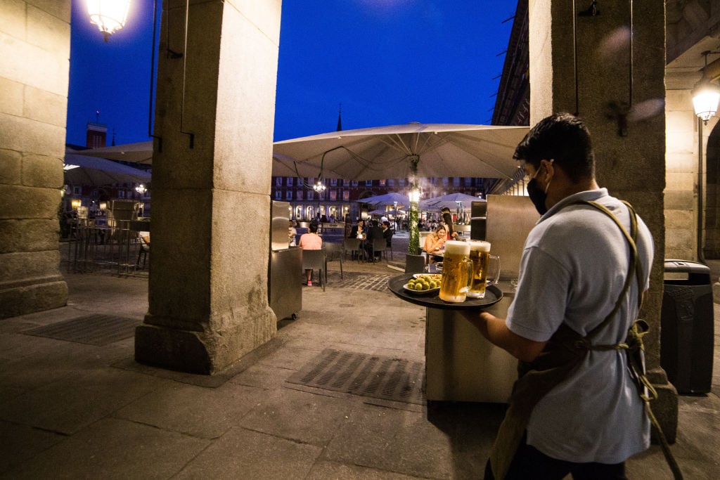 Un camarero sirve comida de noche en una terraza.