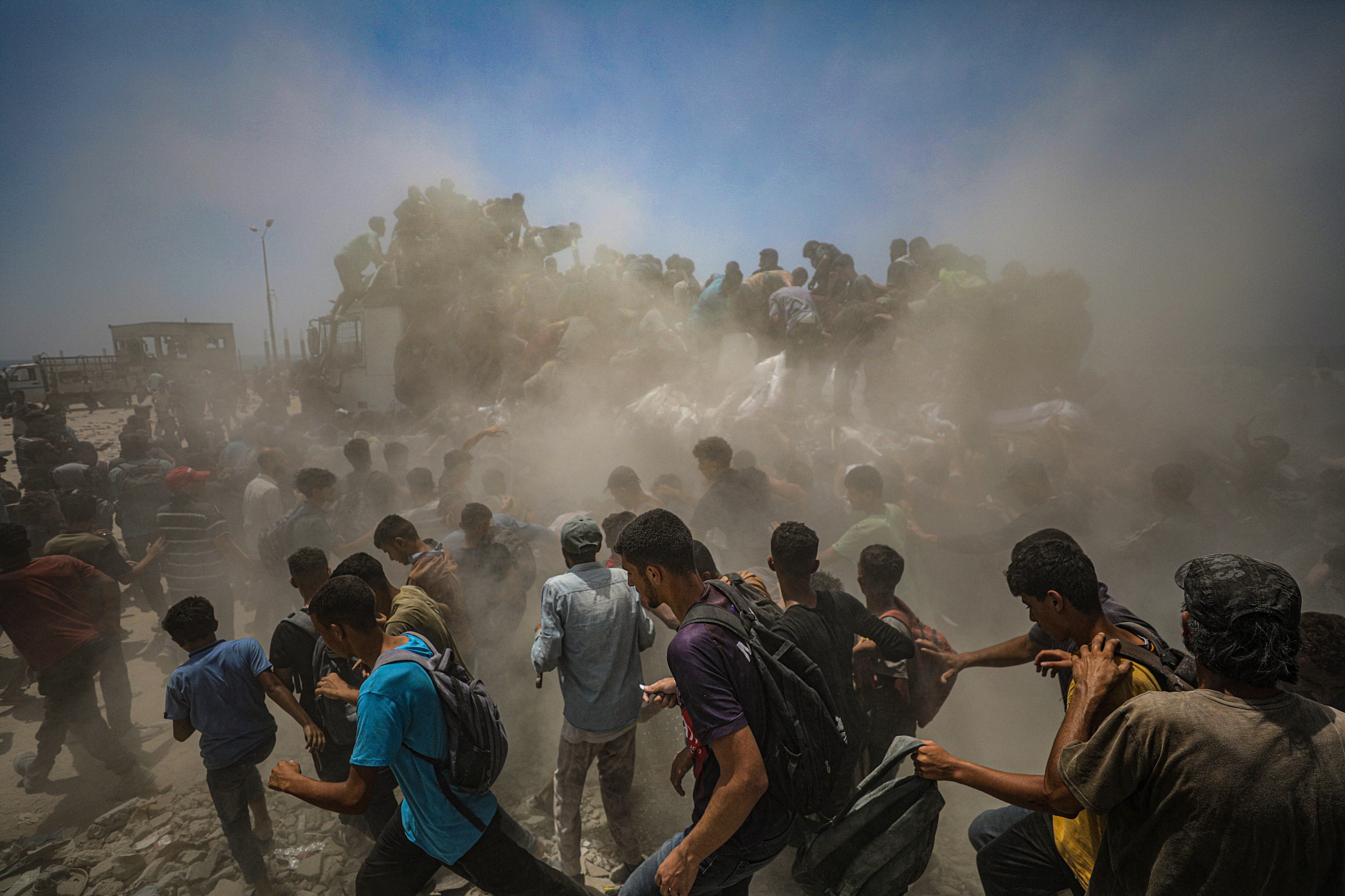 Palestinos intentan conseguir sacos de harina de un camión cerca de un punto de distribución de ayuda en Zikim