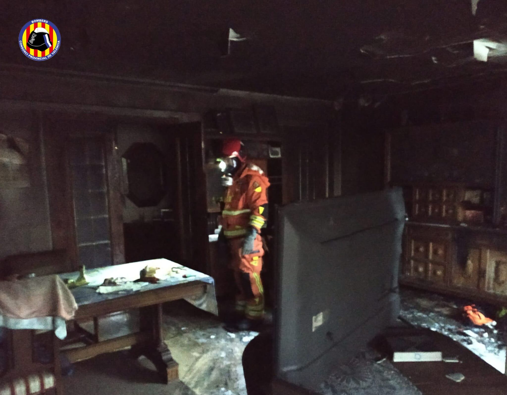 Uno de los bomberos en el interior de la vivienda incendiada en Tavernes de la Valldigna.