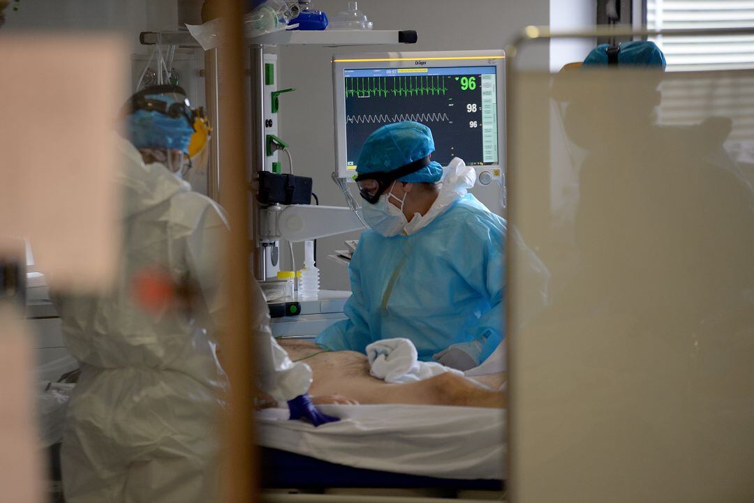 Personal sanitario atendiendo a un paciente de COVID-19 en la UCI.