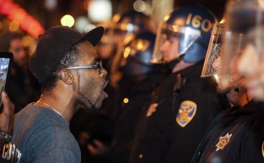 Un manifestante grita a los agentes de policía durante una manifestación en contra de la decisión del gran jurado de Ferguson, en San Francisco, California