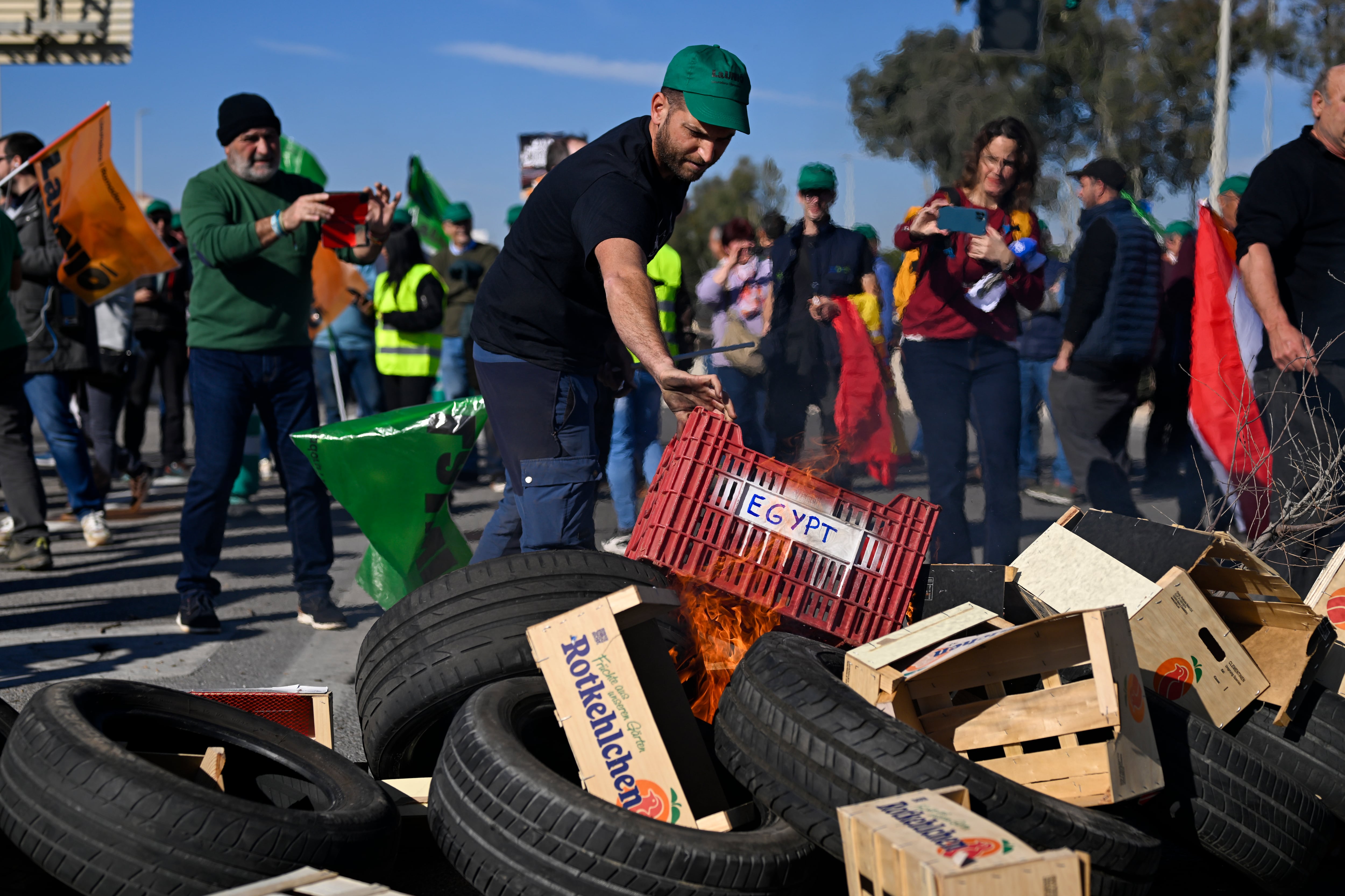 GRAFCVA8182. CASTELLÓN DE LA PLANA, 07/02/2024.- Un agricultor apila una caja con la etiqeuta &quot;Egypt&quot; en la barrera que corta el acceso al Puerto de Castellón durante la concentración convocada por la Unió Llauradora i Ramadera para denunciar la competencia desleal que se produce con las importaciones de países terceros. EFE/Andreu Esteban
