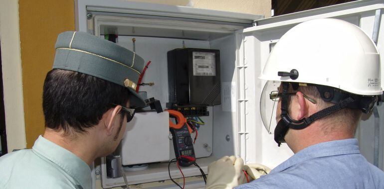 La Guardia Civil inspecciona un contador con la ayuda de un operario de la empresa eléctrica.