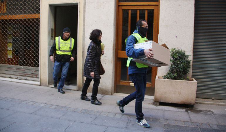 Agents de la Guàrdia Civil surten d'un dels domicilis registrats amb una caixa al carrer la Cort de Valls.