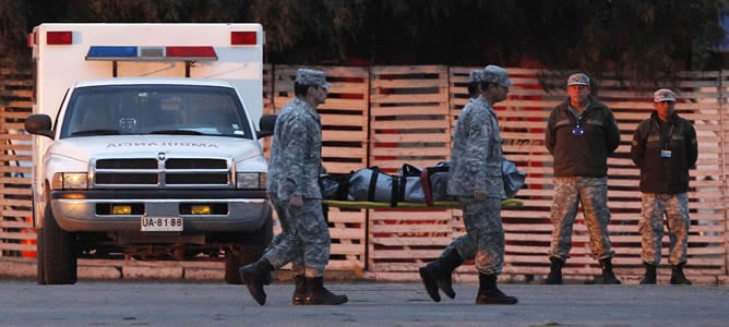 Personal militar mueve uno de los cuerpos encontrados cerca del archipiélago de Juan Fernández, en una base aérea, en Santiago.