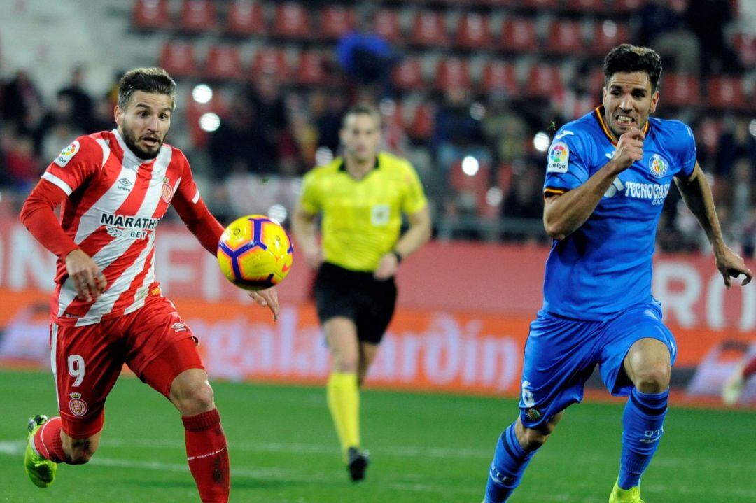 El centrocampista del Girona FC, Cristian Portugués, persigue el balón ante el defensa del Getafe CF, Leandro Cabrera