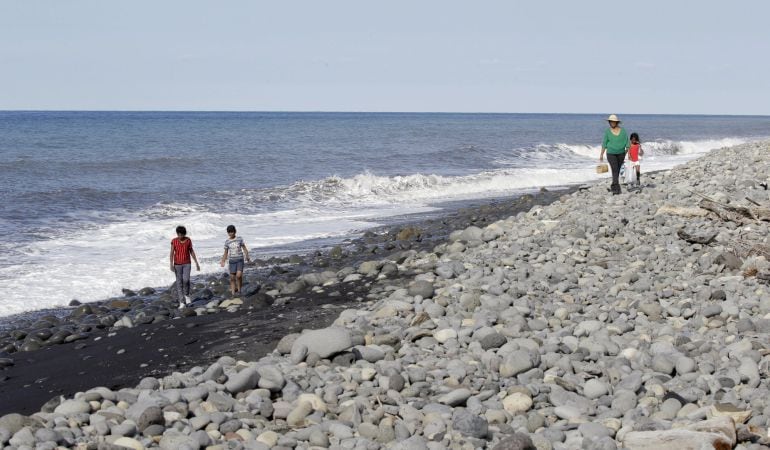 Gente caminando por la playa en la se encontraron escombros de avión situada en la isla francesa de La Reunión.