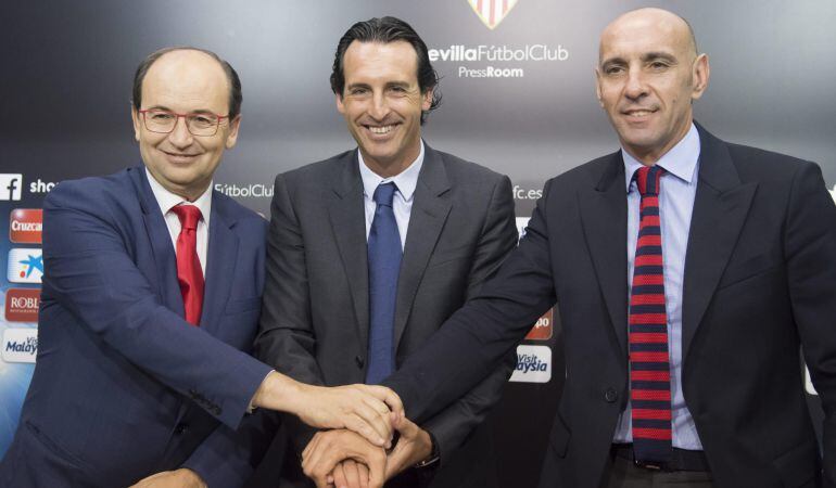GRA309 SEVILLA, 12/06/2015.- El presidente del Sevilla F.C, José Castro (i), junto al director deportivo, Ramón Rodriguez "Monchi" (d), estrechan las manos con el entrenador Unay Emery, tras la ampliación de su contrato hasta junio de 2017 con el club de Nervión. EFE/Raúl Caro