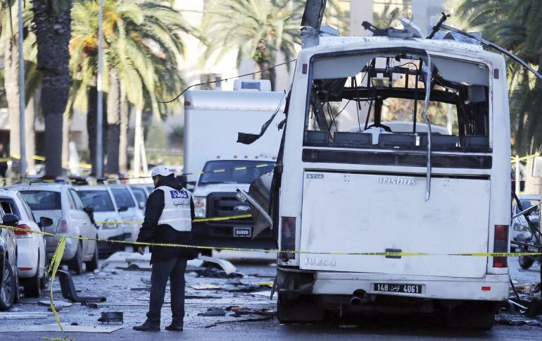 Policías forenses tunecinos inspeccionan los restos de un autobús tras el atentado contra varios guardias presidenciales que se encontraban a bordo del vehículo