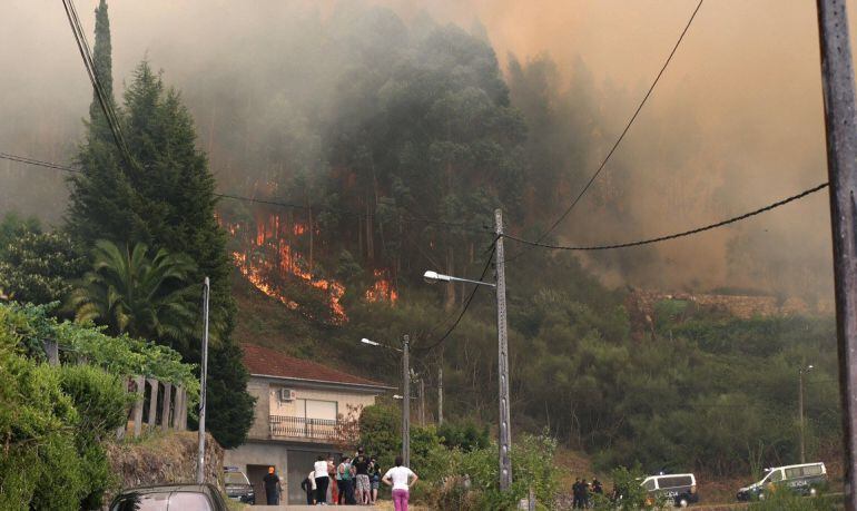 Las llamas cerca de una vivienda en el incendio forestal registrado en el sur de Galicia, en Soutomaior (Pontevedra), que se ha originado sobre las cuatro de esta tarde. Un amplio dispositivo, formado por agentes, brigadas y medios aéreos, trabaja con int