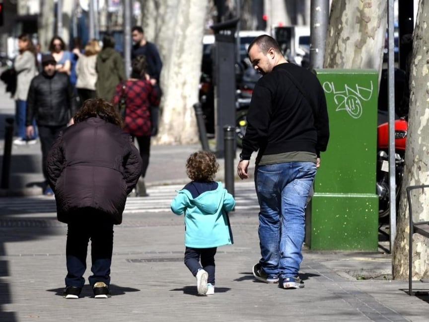 Unos padres pasean junto a su hija por la calle