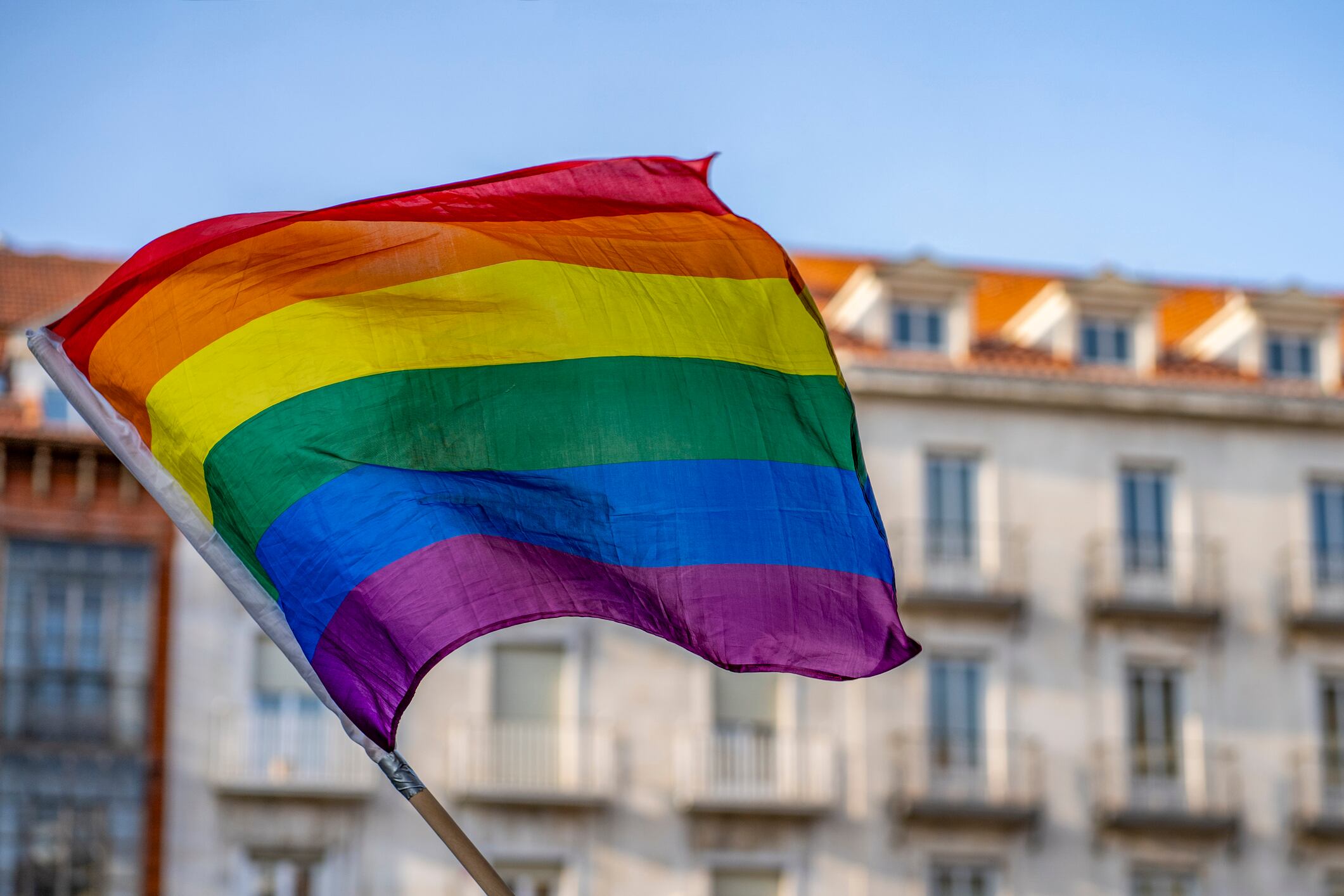 Waving gay flag and crowd of people on background. Concept of LGBT rights and parade