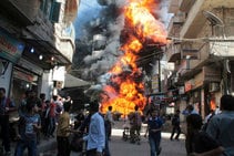 Residente de un barrio de Aleppo huyen de las llamas tras una explosión en la tienda de gasolina y aceite. Testigos dijeron que el incendio fue causado por una bala disparada por un francotirador leal al presidente sirio Al Assad.