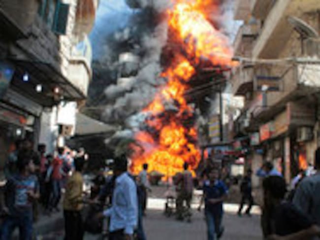 Residente de un barrio de Aleppo huyen de las llamas tras una explosión en la tienda de gasolina y aceite. Testigos dijeron que el incendio fue causado por una bala disparada por un francotirador leal al presidente sirio Al Assad.