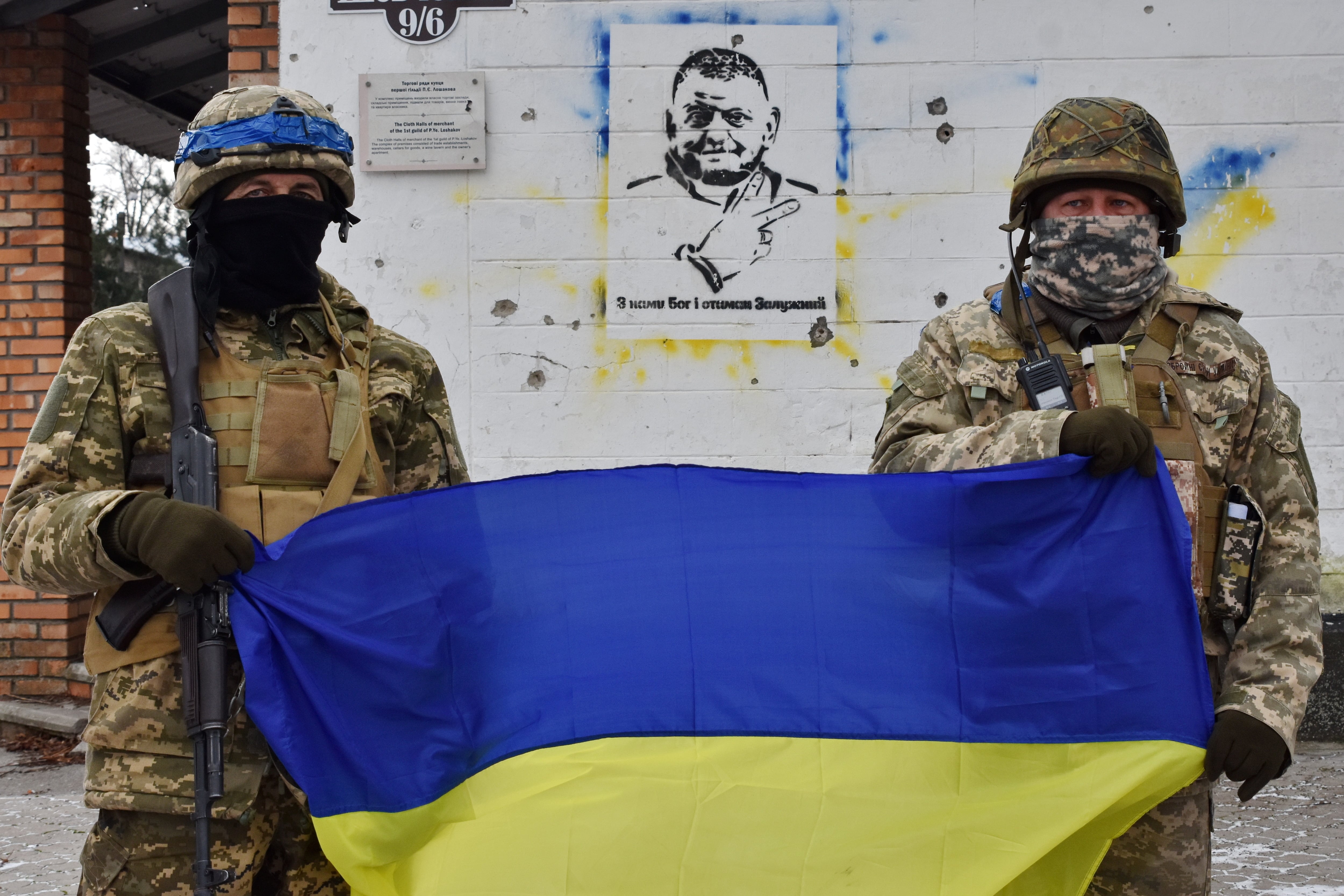 Dos soldados ucranianos sostienen una bandera de su país en la ciudad de Juliaipole