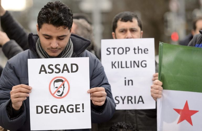 Un hombre sostiene un cartel con las palabras &quot;¡Asad, fuera!&quot; durante una manifestación organizada en Ginebra.