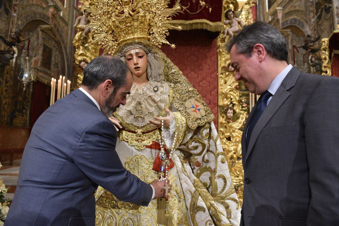 El alcalde de Sevilla, Juan Espadas, junto al hermano mayor de La Trinidad, Juan Manuel Piñas, impone a la Virgen de la Esperanza la Cruz al Mérito con Distintivo Blanco de la Policía Local