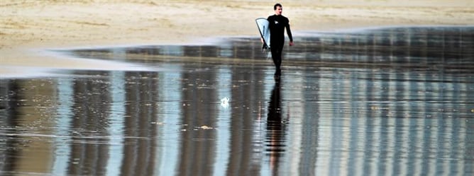 Un surfista pasea por la playa de la Concha, en San Sebastián, el 28 de diciembre de 2011