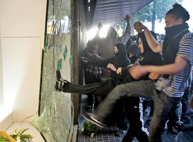 Un grupo de manifestantes rompe un escaparate de unos grandes almacenes del centro de Barcelona, durante los disturbios ocurridos en la jornada de huelga general (EFE)