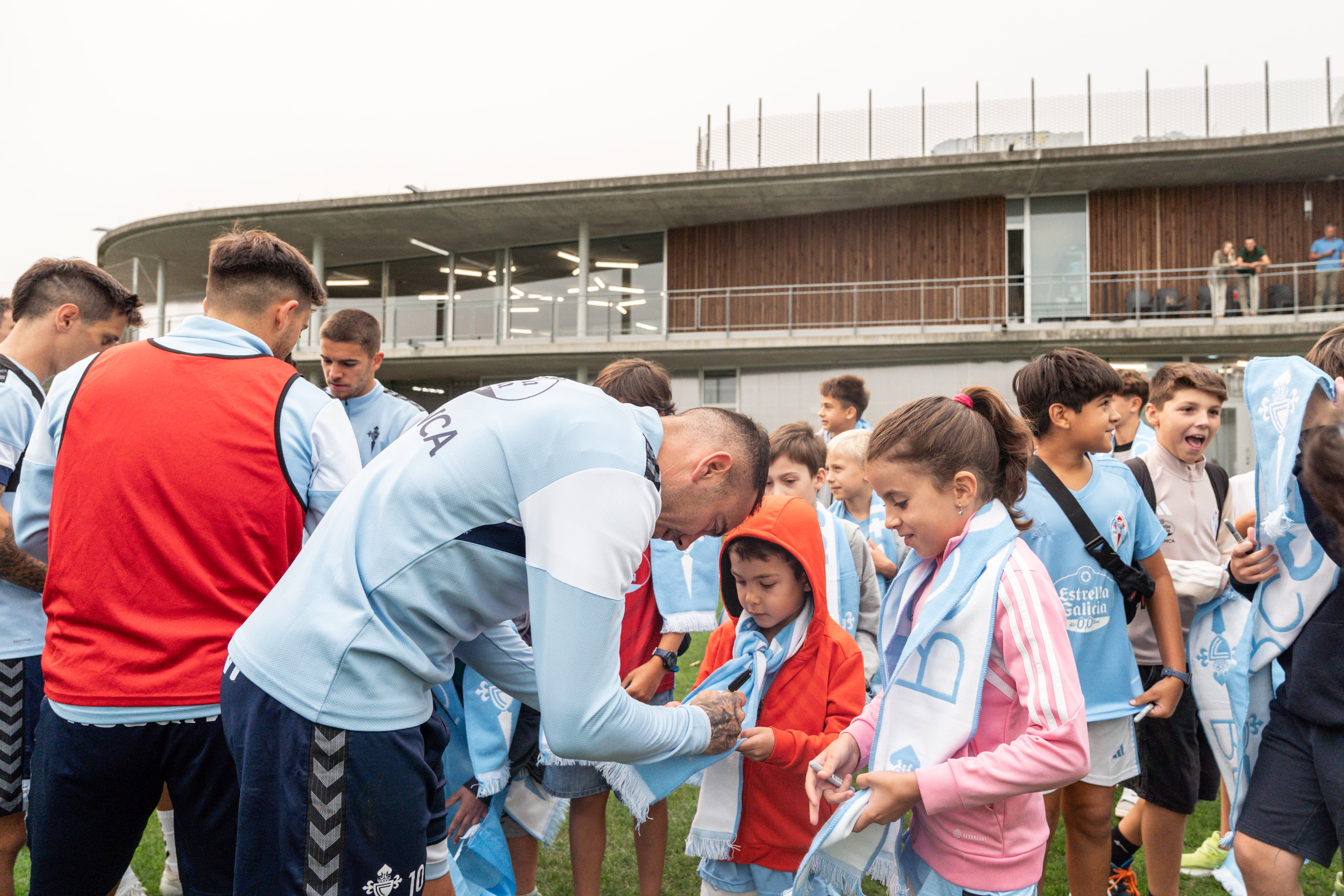 Iago Aspas firma las bufandas de varios de los niños del Cunqueiro que fueron de visita a Afouteza