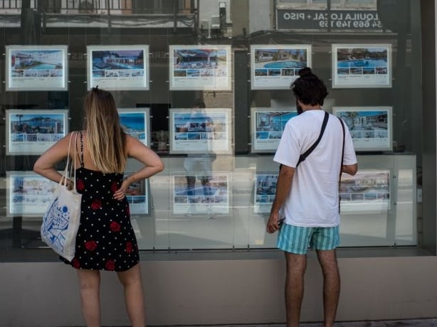 Archivo - Dos personas observan inmuebles en alquiler y en venta en un escaparate de una inmobiliaria ubicada en Palma.