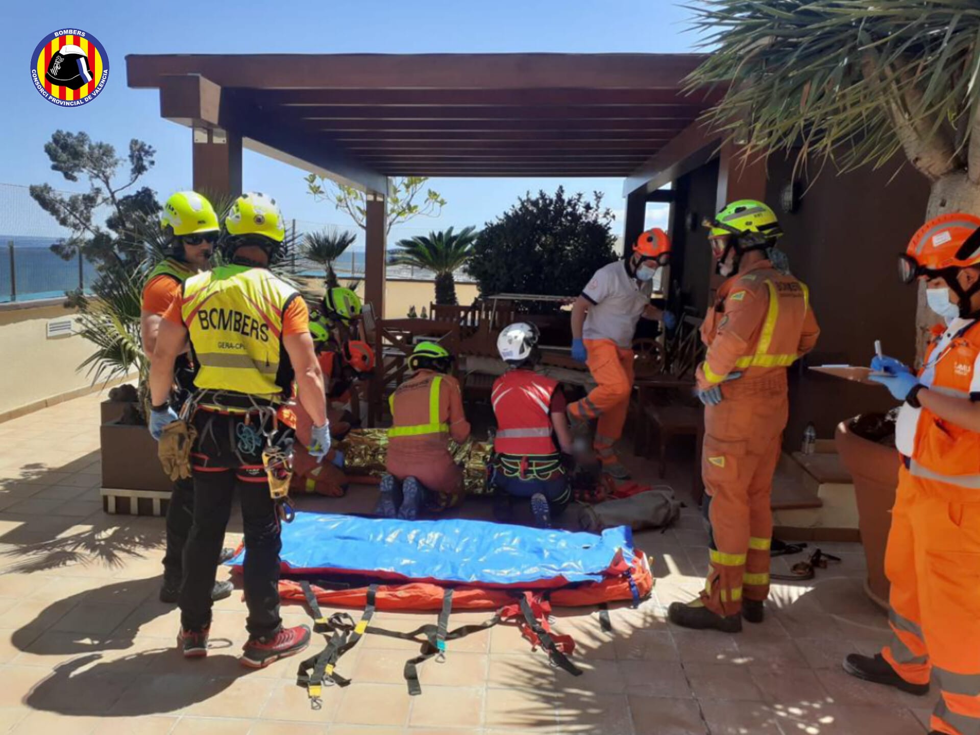 Bomberos y equipo médico atendiendo al herido en la terraza a la que ha caído.