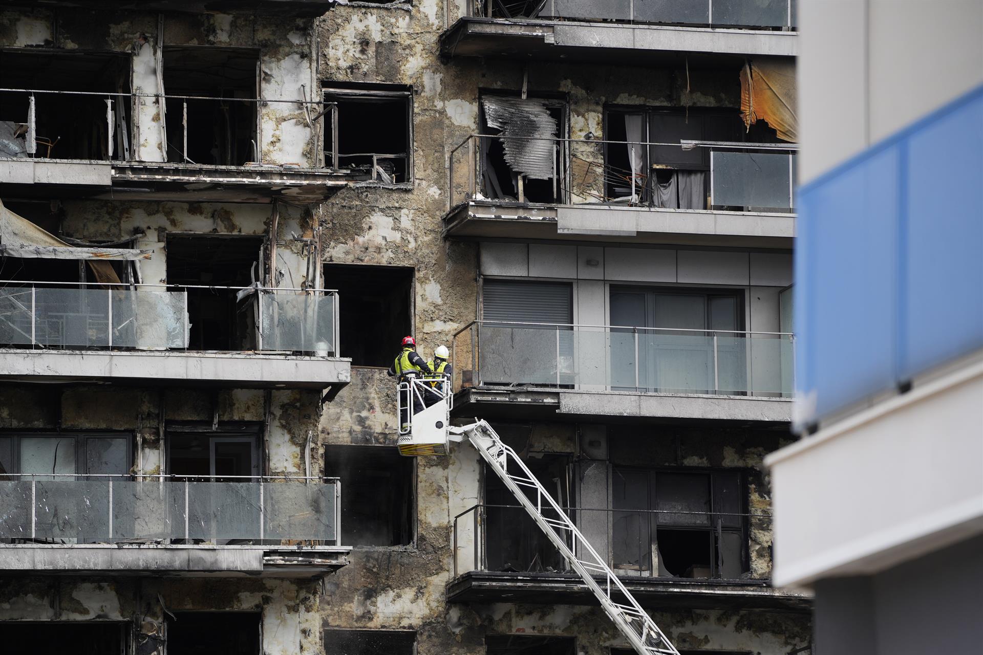 Bomberos en una grúa sanean la fachada quemada del edificio de Campanar en València