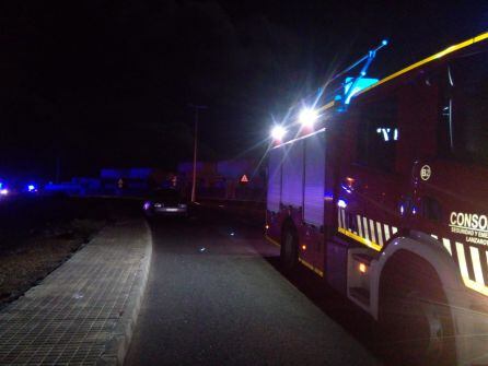 Los bomberos junto al vehículo incendiado.