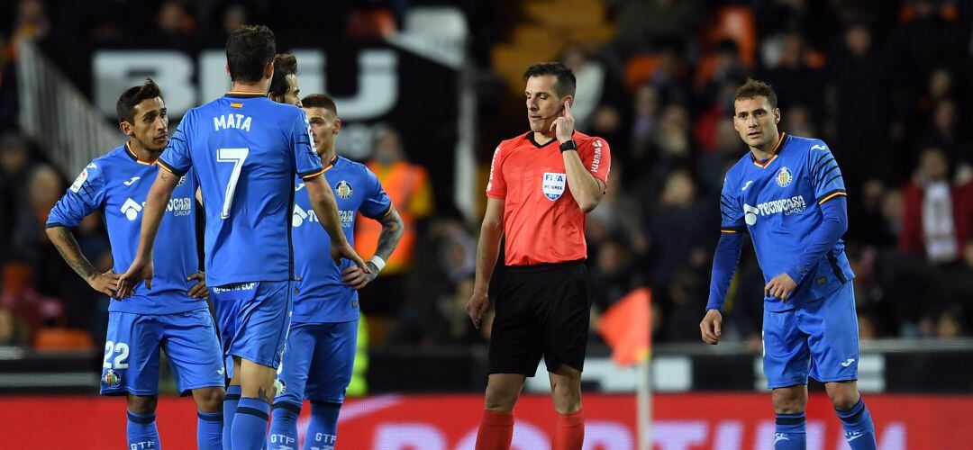 Los jugadores del Getafe C.F. y el árbitro Estrada Fernández durante un momento del partido de Mestalla.