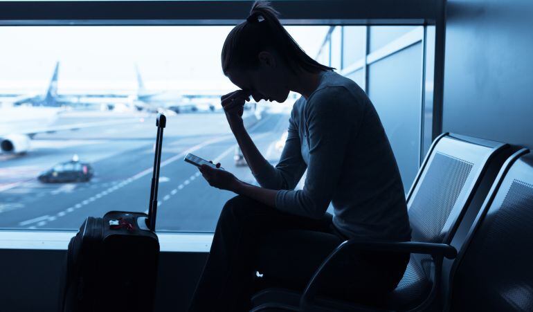 Una mujer consulta su móvil en el aeropuerto.