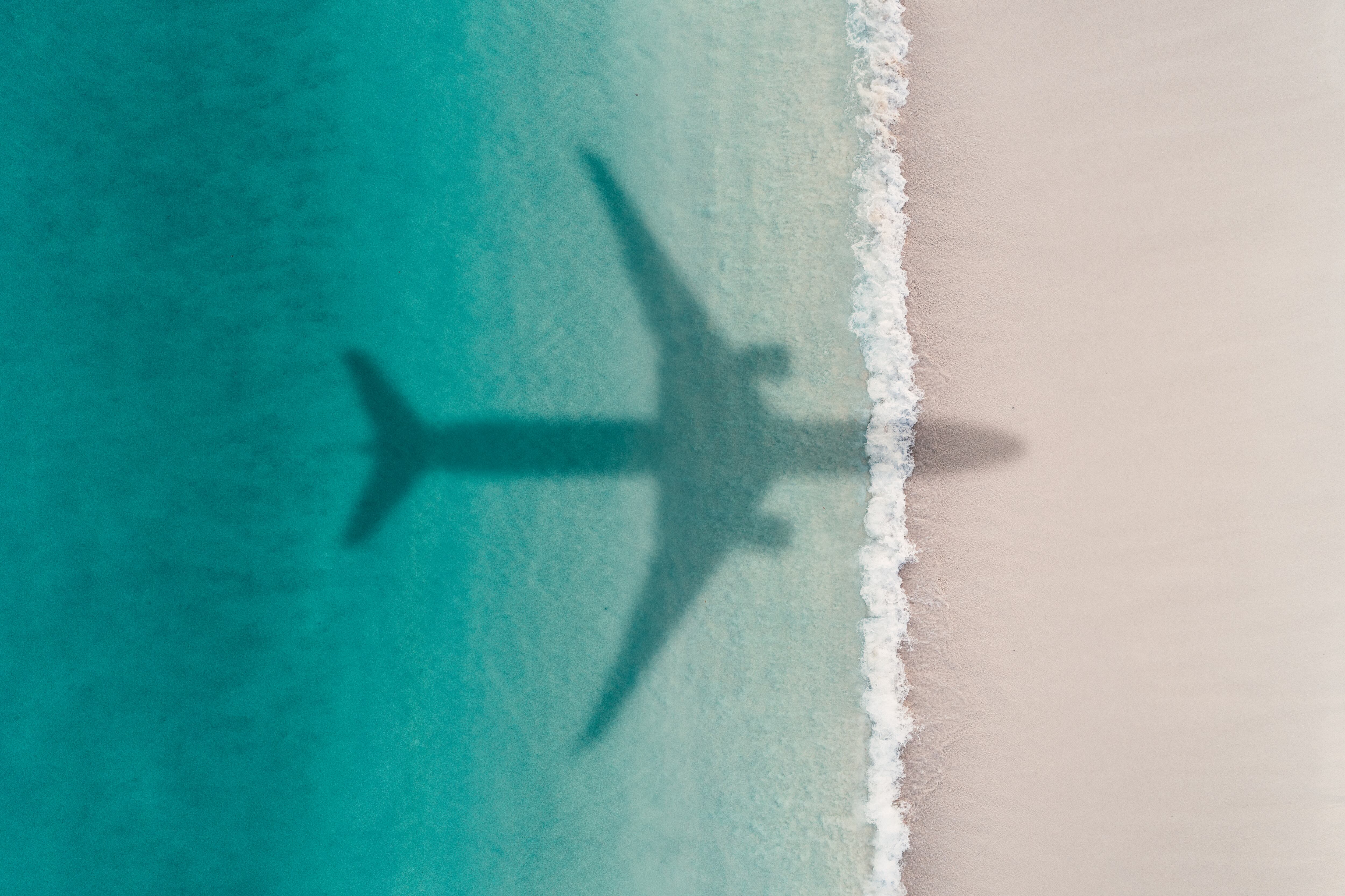 La sombra de un avión sobrevuela una playa.