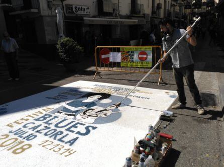 El artista Franc Sánchez da los últimos retoques al cartel del festival en la calle Doctor Muñoz