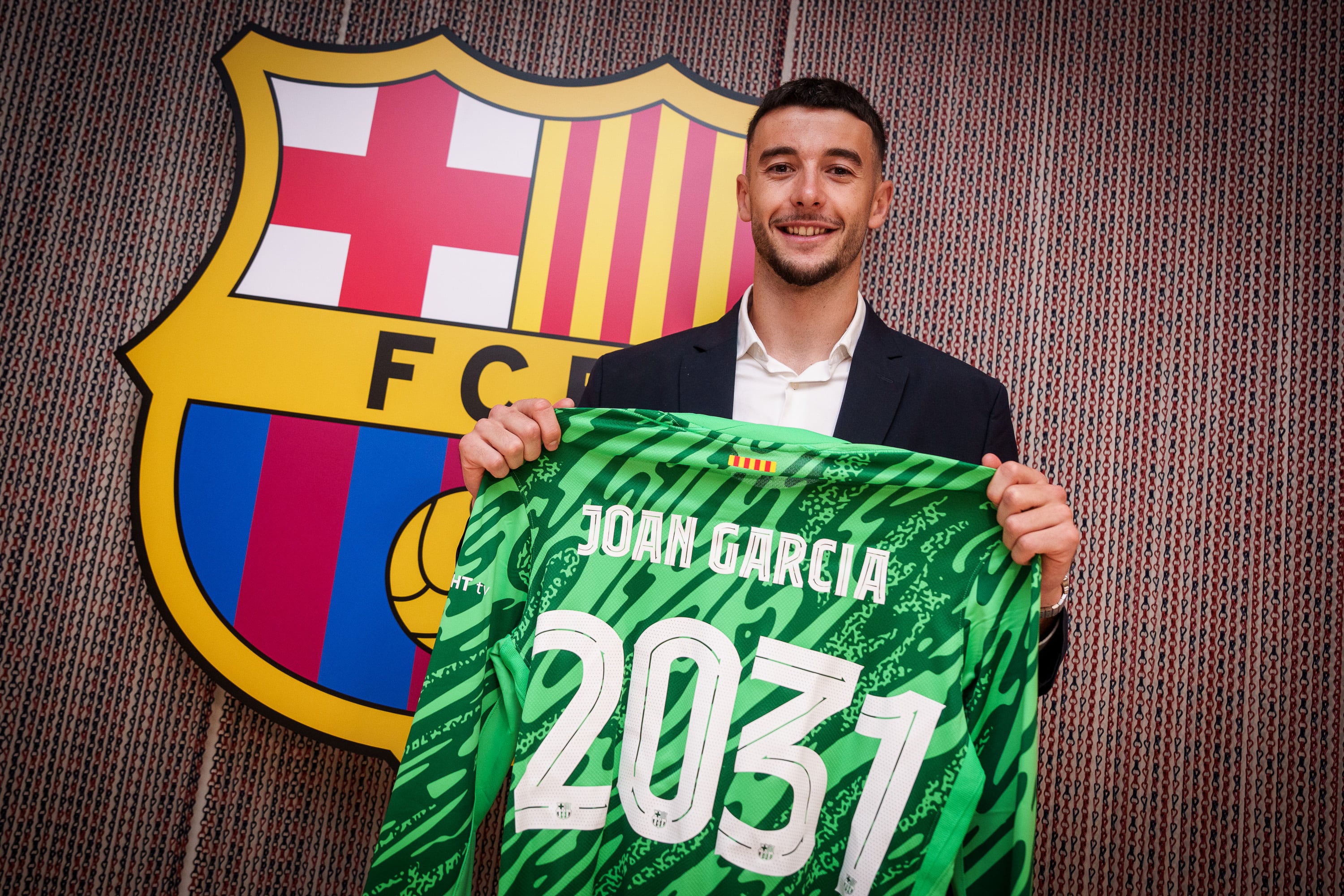 GRAFCAT9675. BARCELONA, 20/06/2025.- El portero Joan García posa junto al escudo tras firmar el contrato con el FC Barcelona hasta 2031 en un acto privado en las oficinas de su nuevo club. EFE/FC Barcelona/German Parga ***SÓLO USO EDITORIAL/SOLO USO PERMITIDO PARA ILUSTRAR LA NOTICIA QUE APARECE EN EL PIE DE FOTO*** (CRÉDITO OBLIGATORIO)