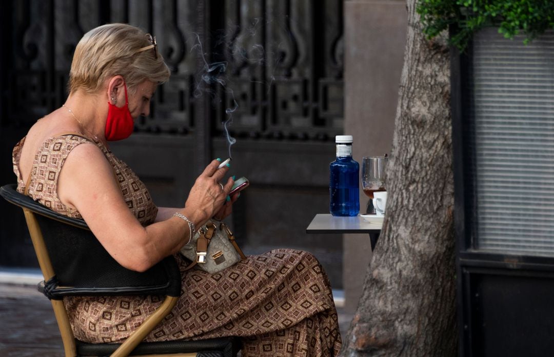 Una mujer fuma en la terraza de un bar en València tras entrar en vigor las limitaciones al tabaco en toda España.