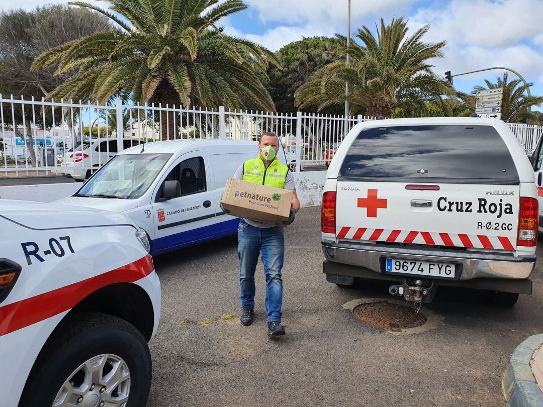 Uno de los encargados del reparto entregando alimentos en Cruz Roja para que esta los distribuya entre familias con mascotas.