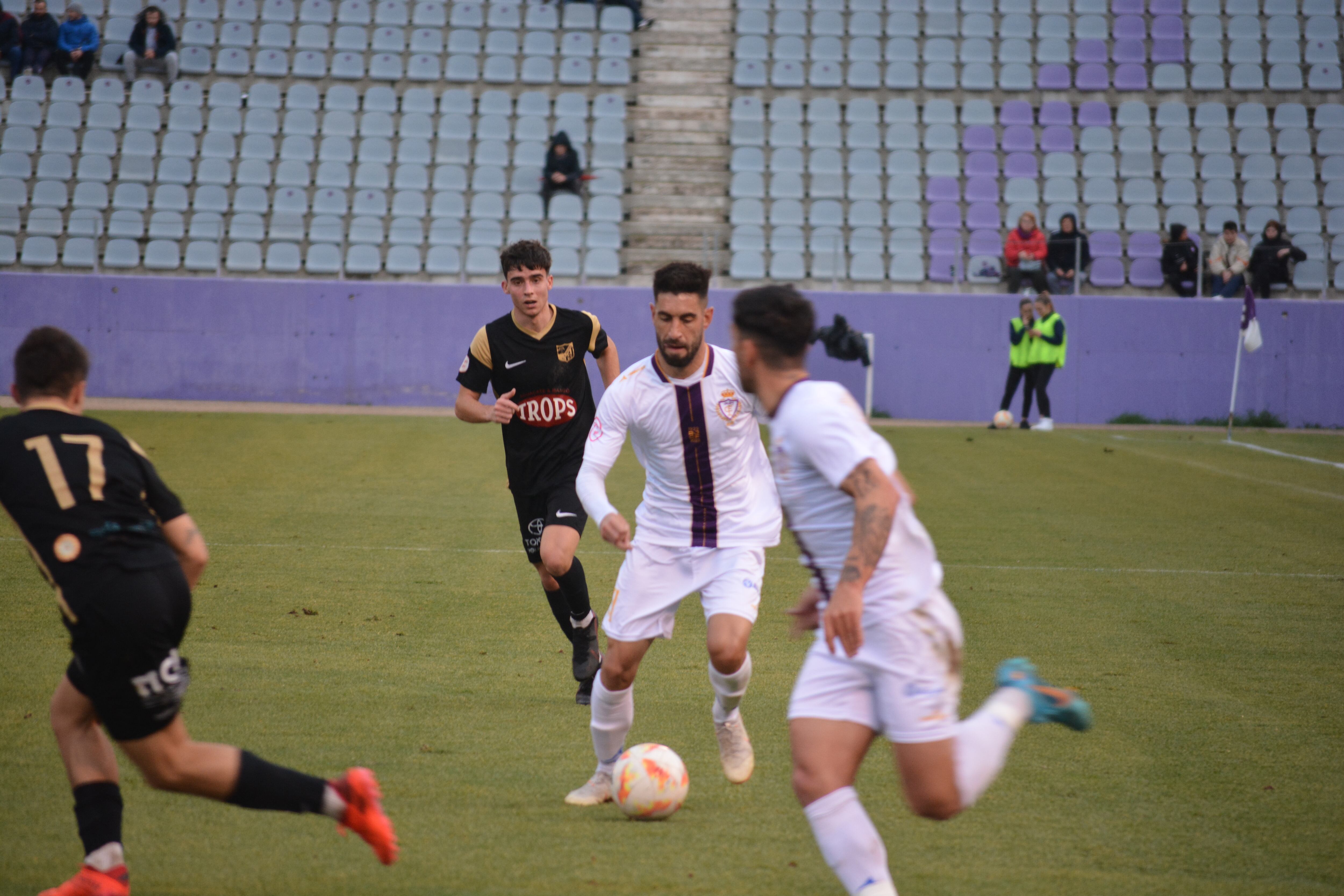 El jugador del Real Jaén Mario Martos conduce el balón entre dos futbolistas del Motril