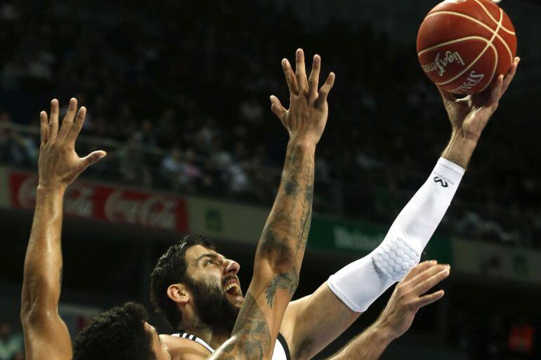 GRA121. MADRID, 16/11/2014.- El pívot griego del Real Madrid, Ioannis Bourousis (d), entra a canasta ante el brasileño del UCAM Murcia, Augusto César Lima (i), durante el partido de la sétima jornada de la liga ACB de baloncesto disputado hoy en el Palaci