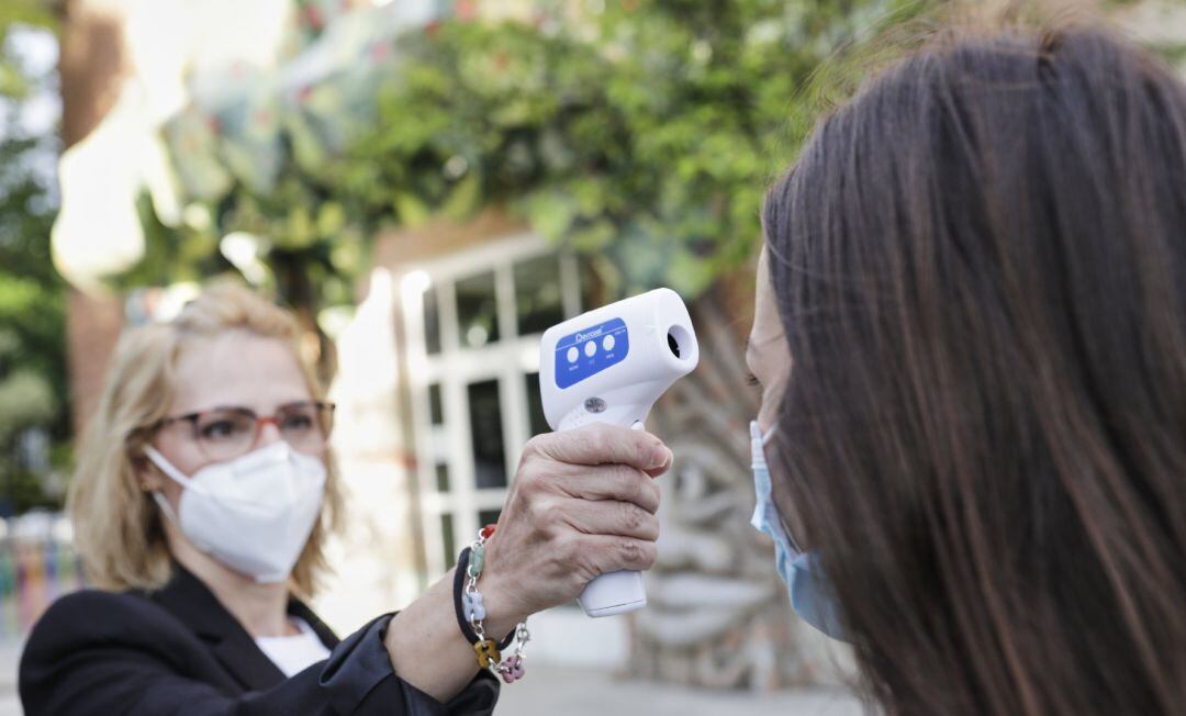 Una profesora le toma la temperatura a una alumna en una foto de archivo.