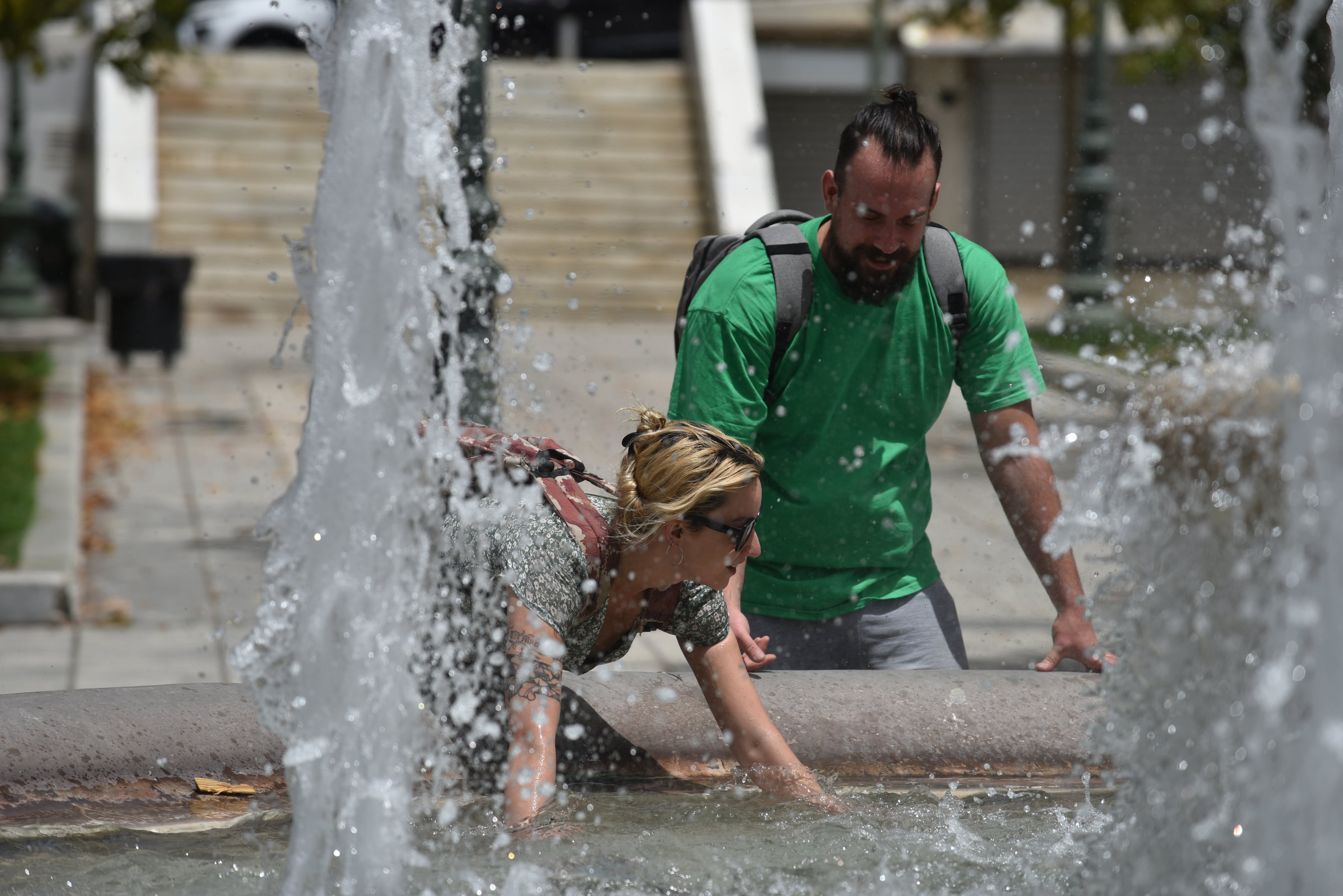 Dos personas se refrescan en la Plaza Sintagma de Atenas en plena ola de calor en la capital griega