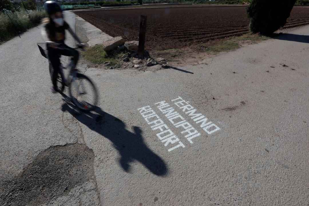 Un niño pasea en bicicleta durante su franja horaria hasta el límite de su municipio observando el cartel pintado en el suelo por la Polcía Local avisando del inicio de otro territorio