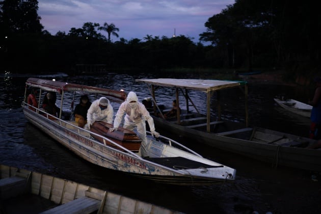 Miembros de SOS Funeral transportan el féretro de una anciana fallecida en Manaos, una de las ciudades brasileñas más afectadas por el coronavirus, donde reinaron el negacionismo y la confusión por los mensajes de los líderes políticos