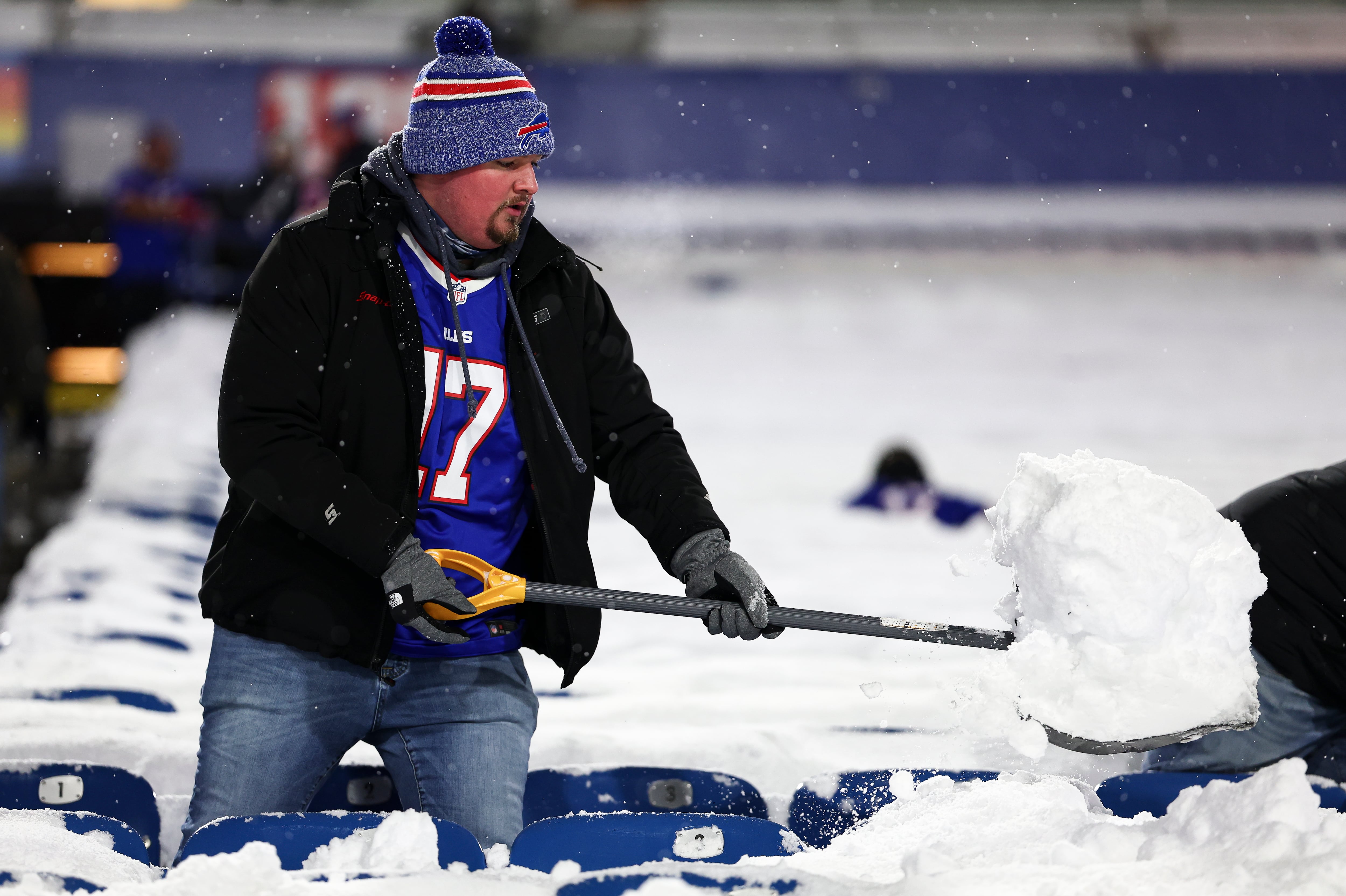 Un aficionado de los Buffalo Bills ayuda a quitar la nieve del Highmark Stadium