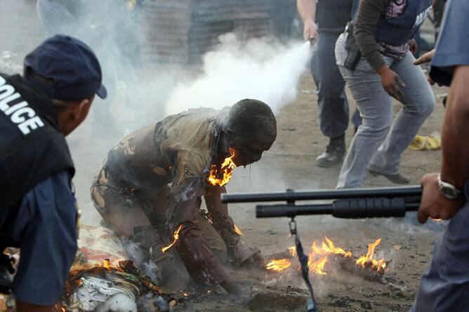 En la imagen, la policía intenta ayudar a un hombre víctima de los ataques xenófobos que está sufriendo Sudáfrica en los últimos 15 días.