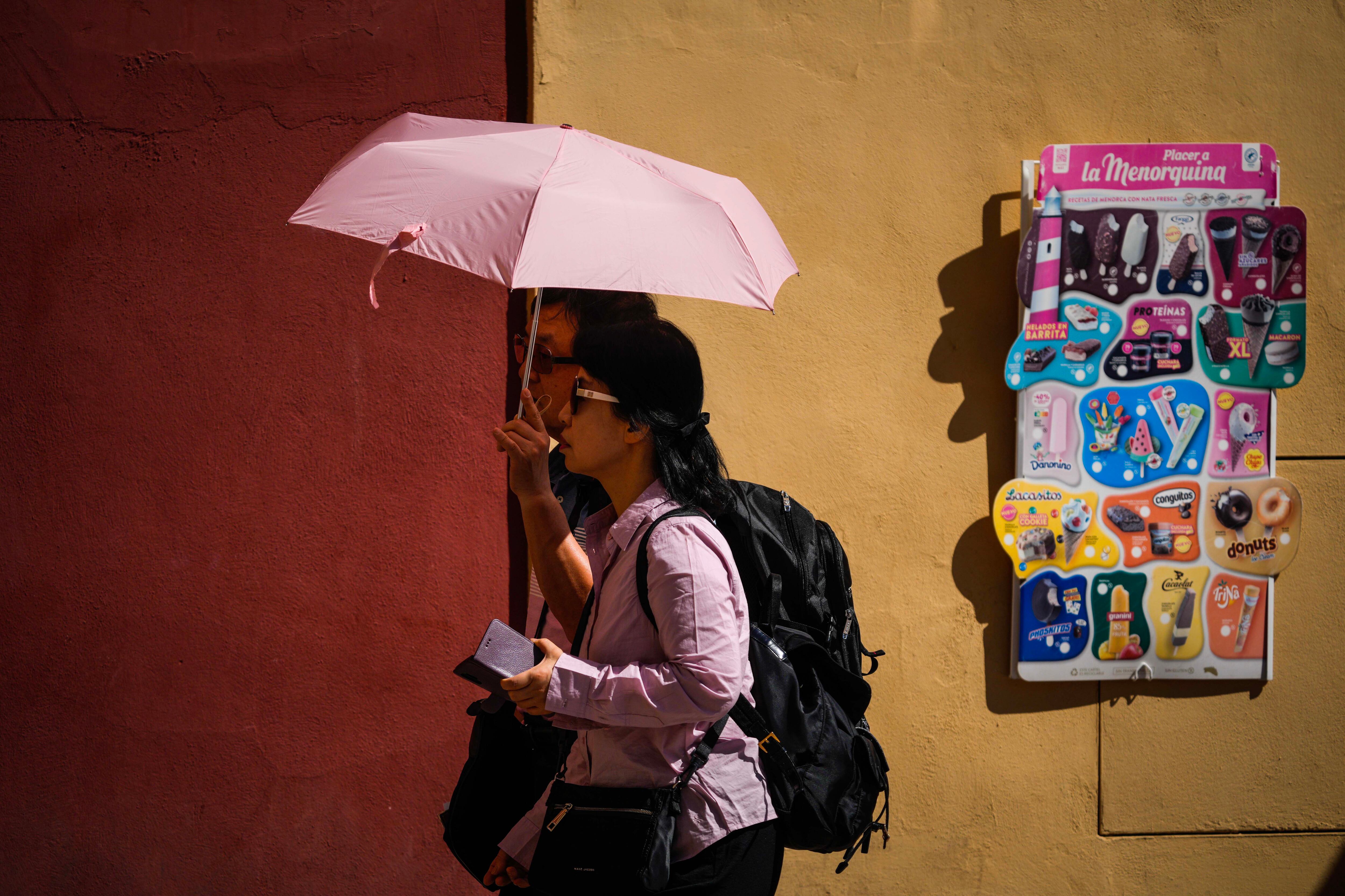 Una pareja de turistas pasea por la judería de Córdoba protegidos por un paraguas