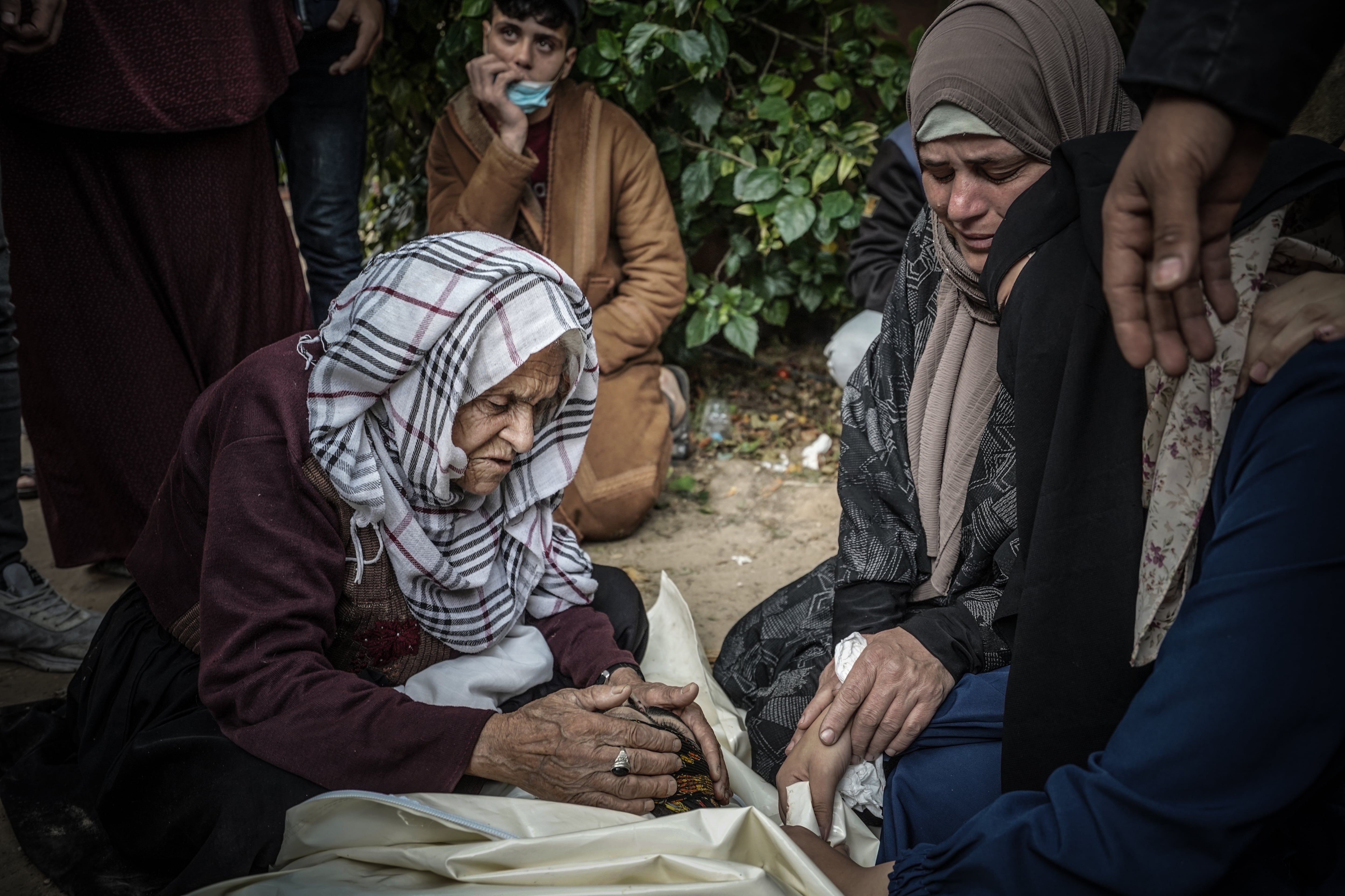 Dos mujeres palestinas lloran ante el cadáver de un hombre después de un ataque aéreo de Israel en Jan Younis